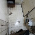 Větrací otvor ve stropě na zdemolovaném pánském WC